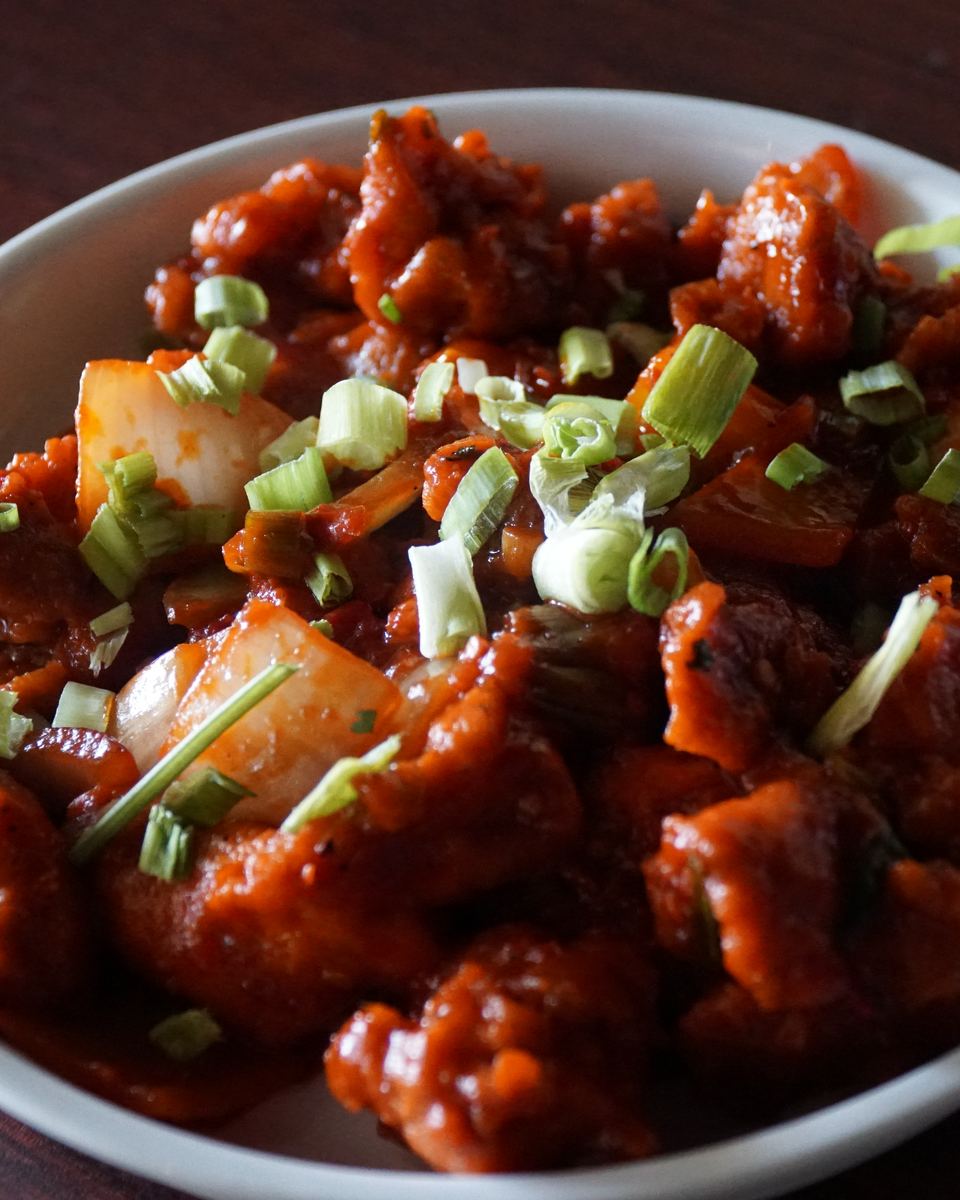 Chilli chicken tossed with onion and topped with spring onion