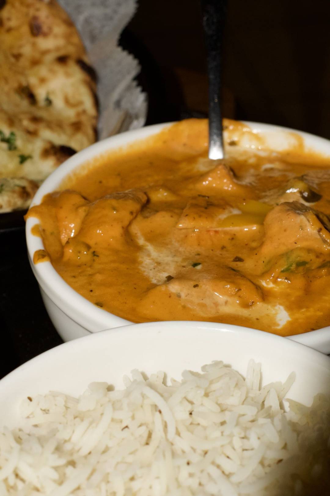 A creamy chicken curry beside basmati rice and naan